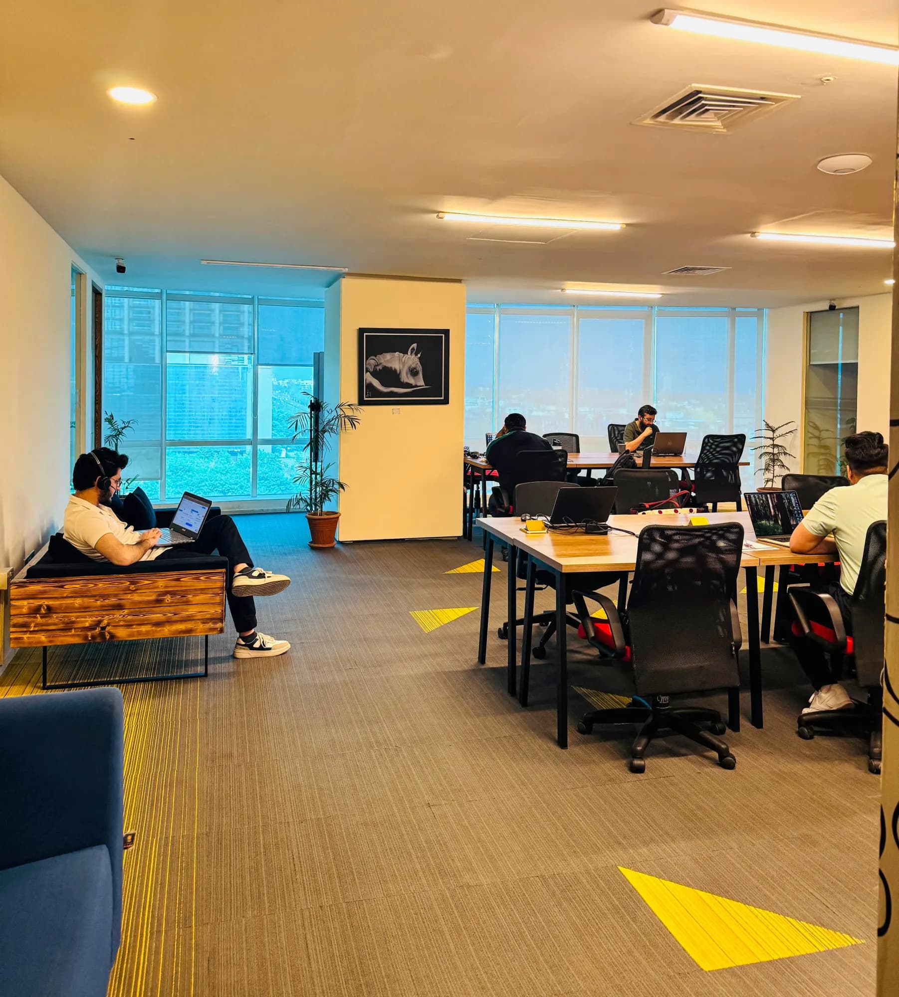 Open coworking area at The Hive Islamabad with members at laptops and a lounge sofa