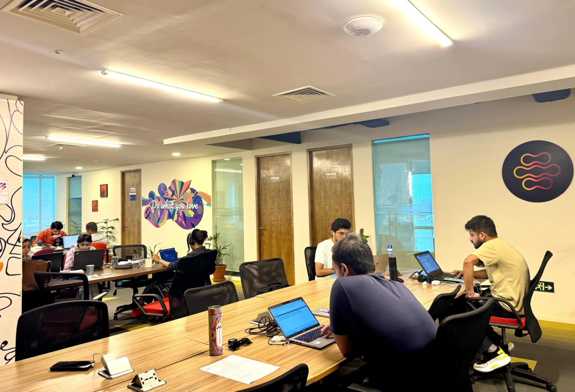 Shared desks at The Hive Islamabad with members working beneath the branded wall logo