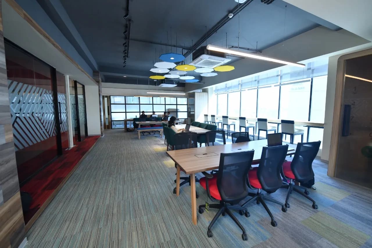 Long open coworking hall at The Hive Karachi with pendant lights and a shared meeting table