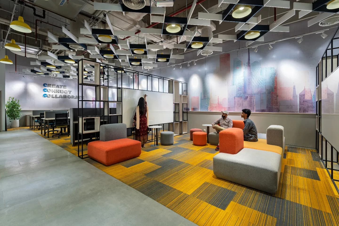Breakout lounge at The Hive Karachi with modular orange sofas and a city-skyline mural