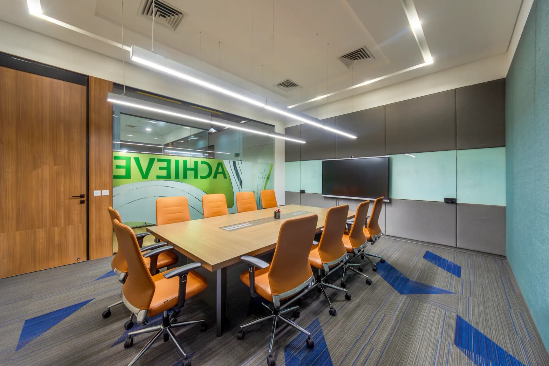 Meeting room at The Hive Karachi with an Achieve glass wall and orange chairs
