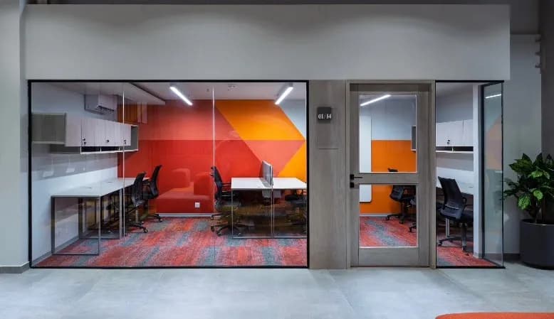 Private office cabin at The Hive Karachi with a red-and-orange geometric feature wall