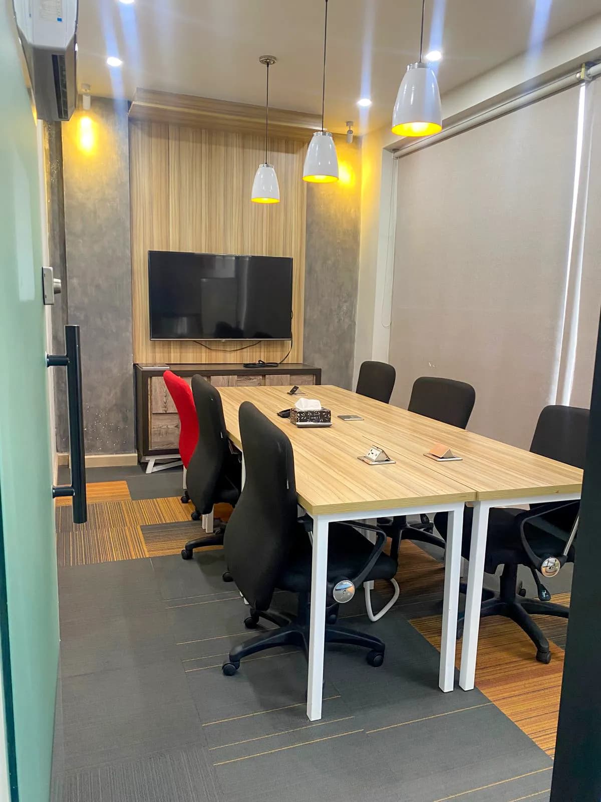 Meeting room at The Hive Lahore with a wall-mounted screen and a wood table