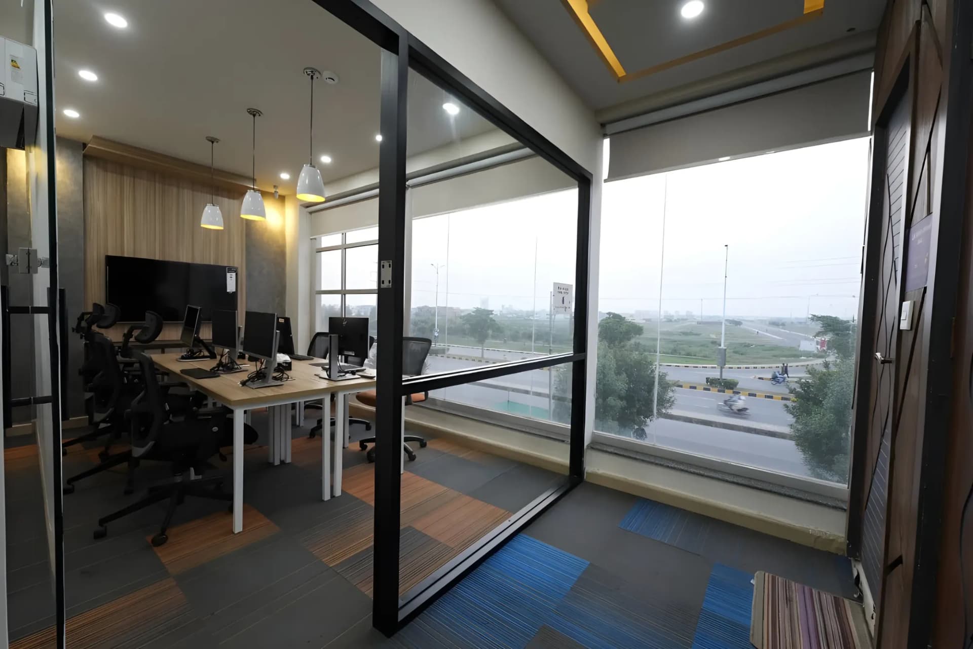 Private office at The Hive Lahore with desks beside a full-height window over the road