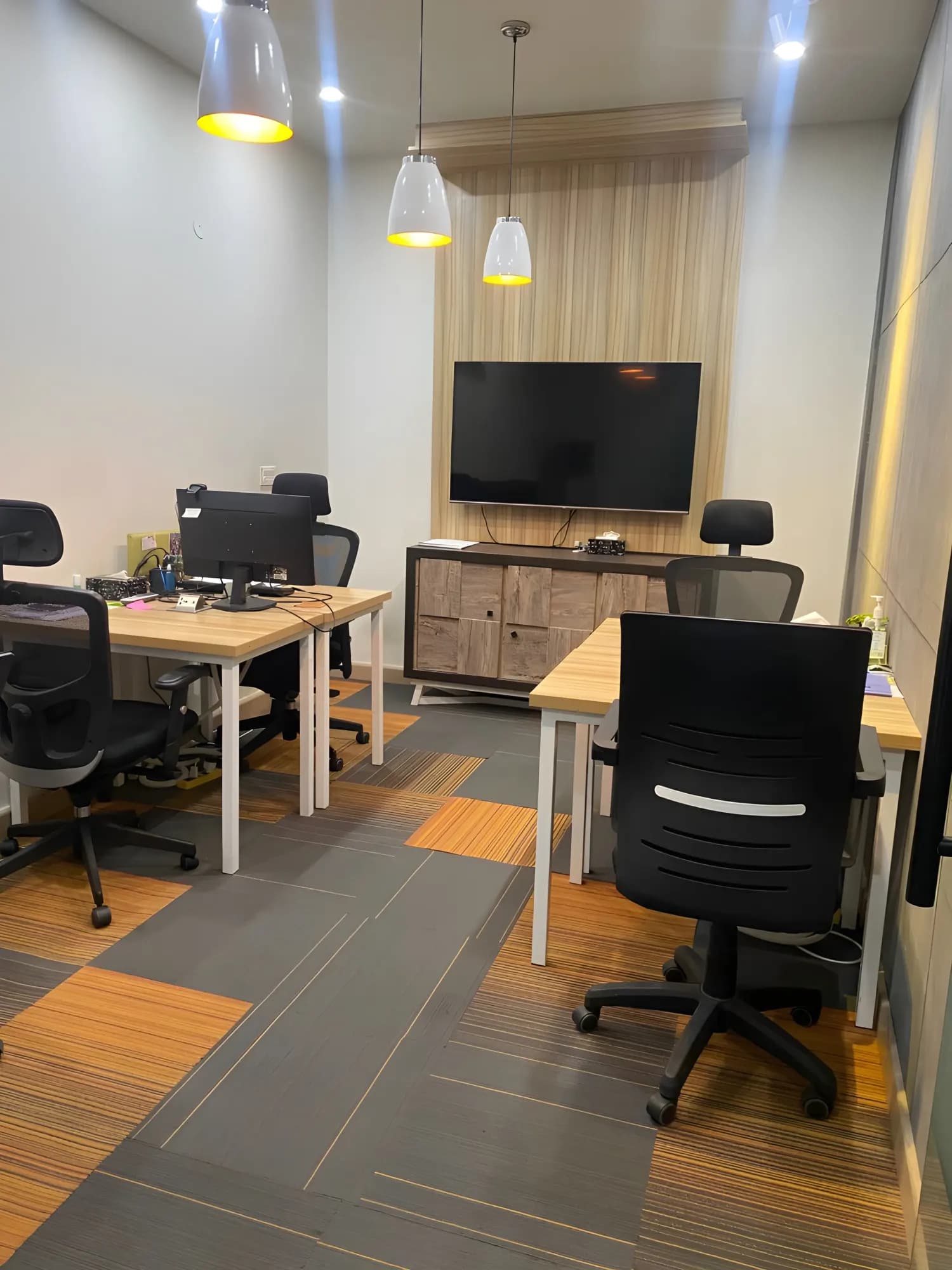 Private office at The Hive Lahore with a wall-mounted screen and wood desks